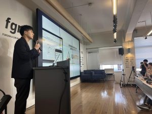室内イベントで登壇し解説する男性