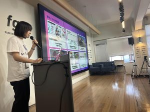 室内イベントで登壇し解説する女性