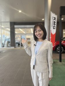 自動車販売企業の前で取材に立つ一人の女性