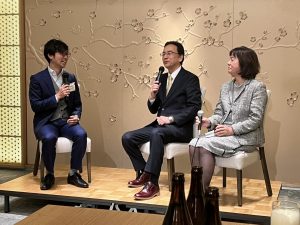 壇上に椅子に座る男性2人と女性1人