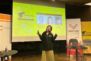 イベント会場でMCの女性がポーズをとる