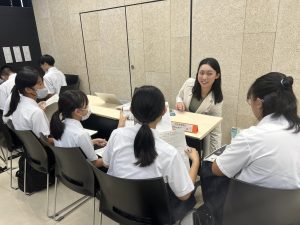 中学生たちに長机を挟んで話す女性