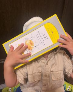 男の子がお菓子の入った箱で顔を隠している