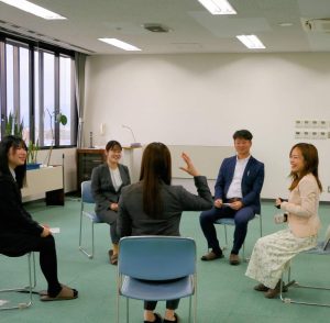 丸く並べられた椅子に座り話をする女性４人男性１人