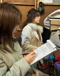 楽屋裏、手に進行表を持つ女性２人