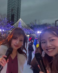 アイスリンクでマイクを持つ女性２人とイルミネーション