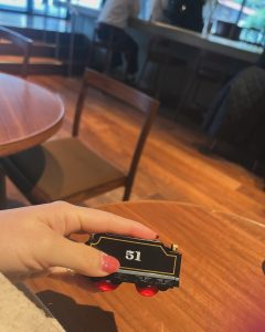 51番と書かれた列車のおもちゃを手に持ち席に座る女性