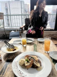 椅子に座る女性の前のテーブルの上にジュースと料理