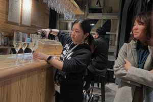 カウンターでシャンパンをつぐ女性とその横に腕を組んだ女性