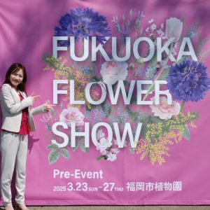 FUKUOKA FLOWER SHOW の垂幕の前でポーズをとる女性