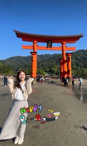 鳥居を前に女性が両手を挙げてポーズ