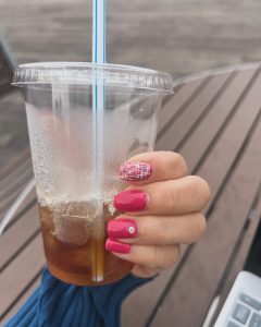 マニキュアを塗った手、アイスコーヒーを手に
