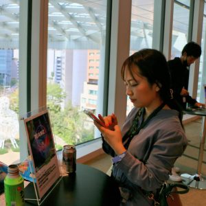 丸テーブルのあるビルの一室でスマホで仕事