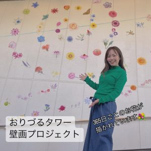 花の絵が描かれた壁の前に女性