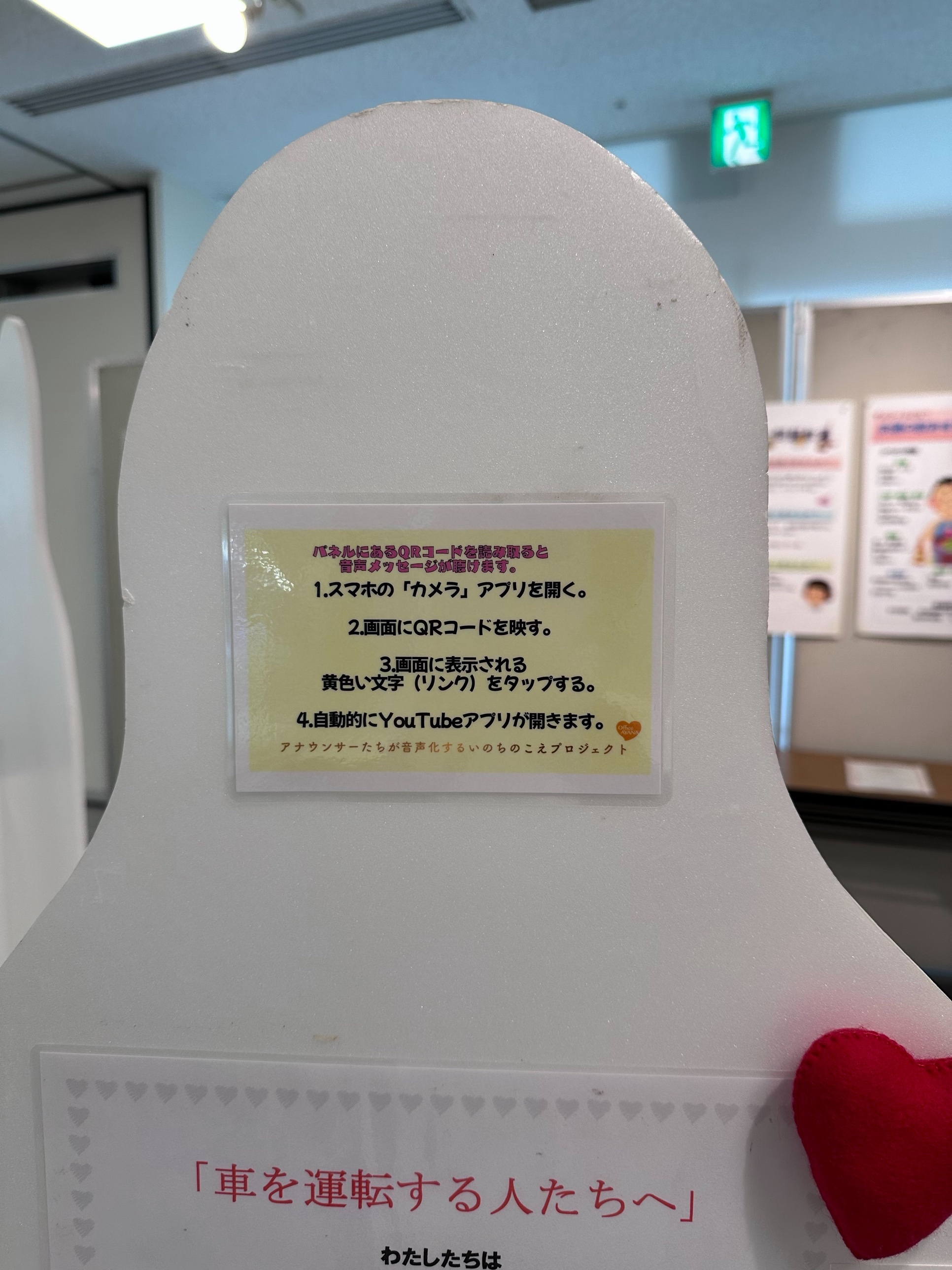会場で案内されているQRコードの読み取り方。スマホのカメラアプリでQRコードを映し、表示されるリンクをタップするとYouTubeで音声メッセージが再生される(福岡市役所会場)